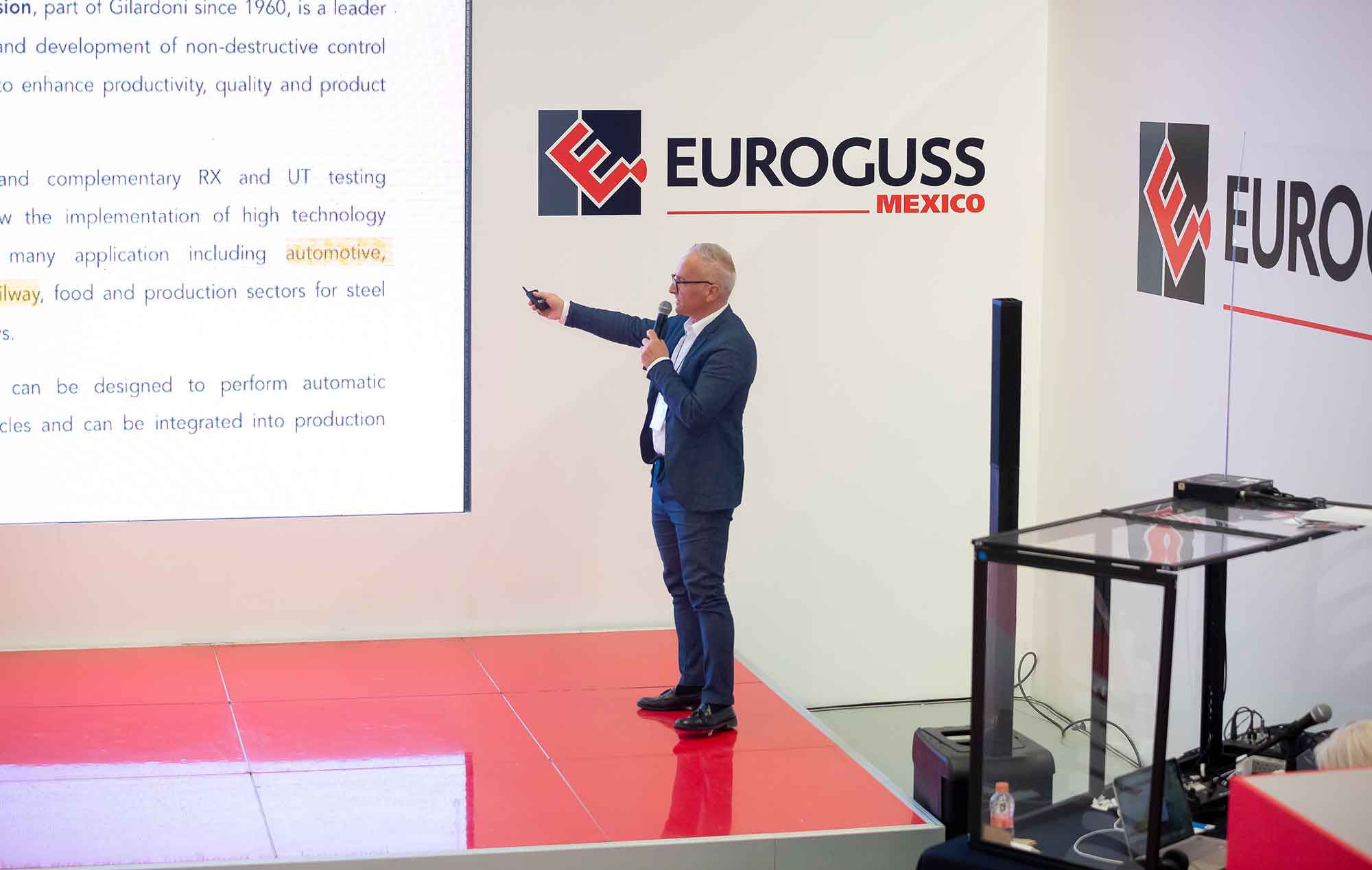 man points at screen while standing on a stage